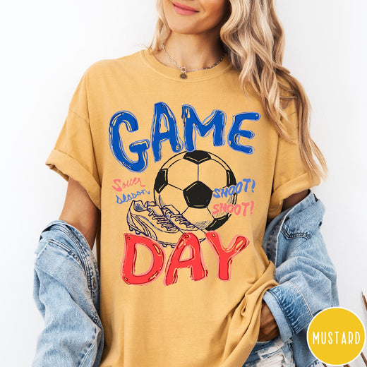 Comfort Colors tee in Mustard featuring soccer graphic with a ball, cleats, and Game Day text