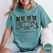 Comfort Colors tee in Seafoam featuring illustrated style graphic of four cats in robes around a candle