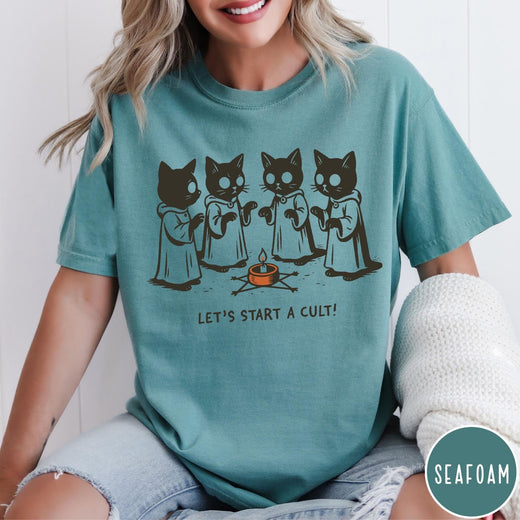 Comfort Colors tee in Seafoam featuring illustrated style graphic of four cats in robes around a candle