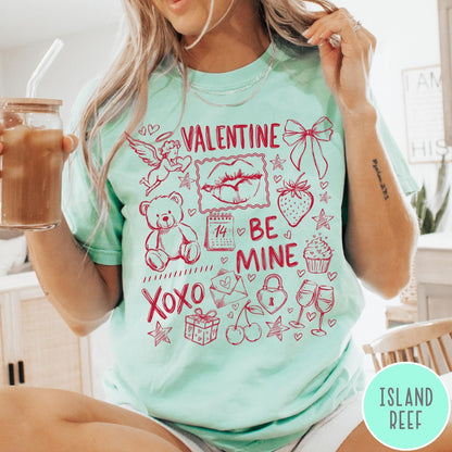 Comfort Colors tee in Island Reef featuring Valentine's Day collage graphic with cupid, teddy bear, and romantic symbols