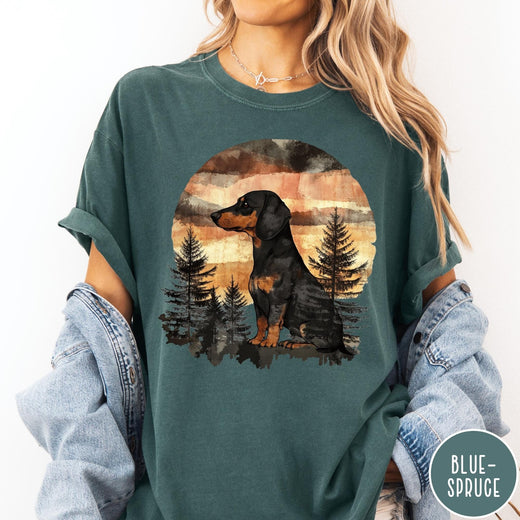 Comfort Colors tee in Blue Spruce featuring vintage style dachshund dog graphic with forest and sunset background