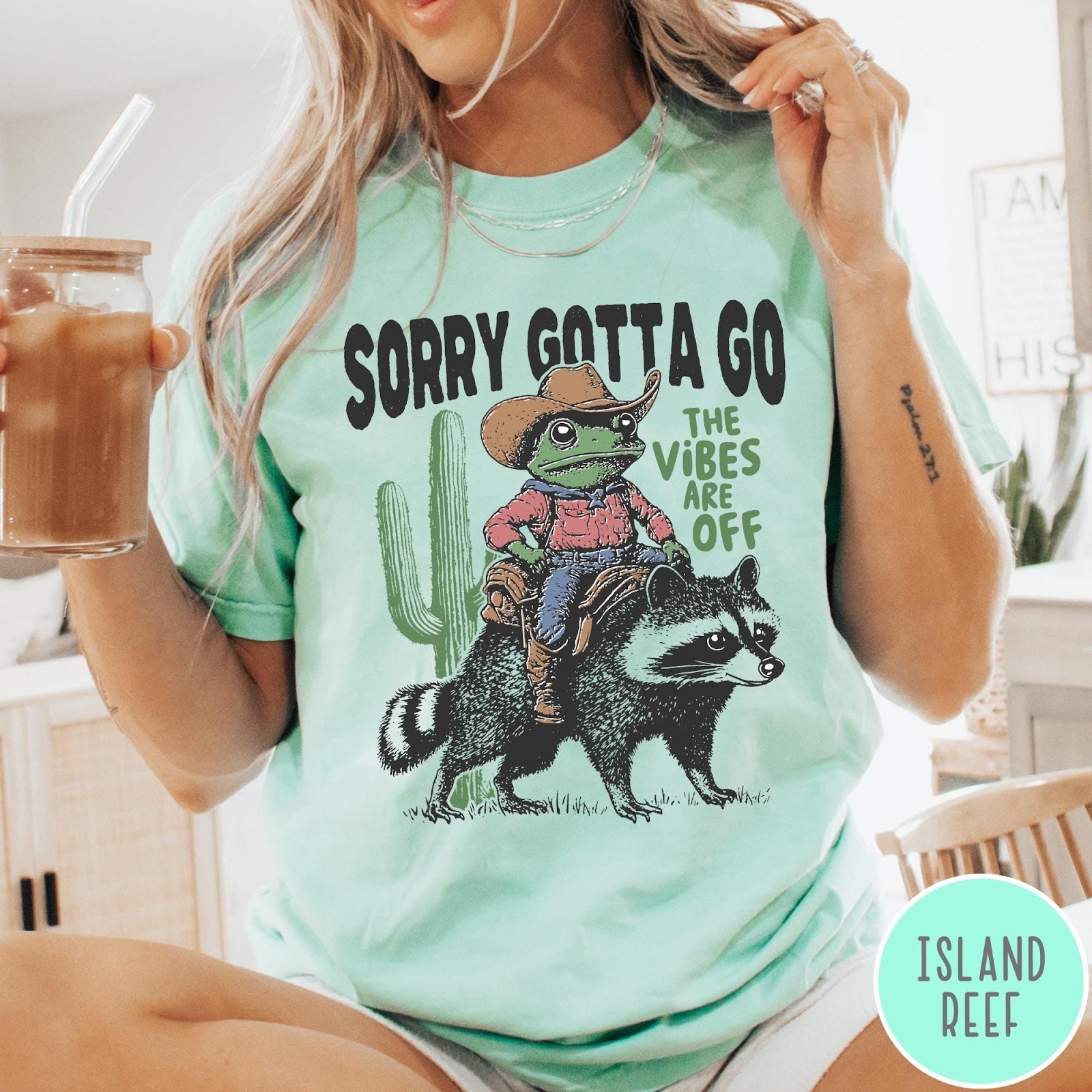 Comfort Colors tee in Island Reef featuring western graphic of a cowboy frog riding a raccoon with cactus