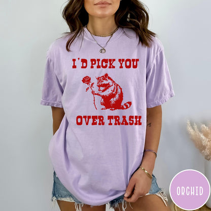Comfort Colors tee in Orchid featuring a whimsical graphic of a raccoon holding a red rose.