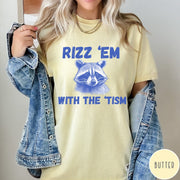 Comfort Colors tee in Butter featuring screen printed raccoon graphic and Rizz Em With the Tism text