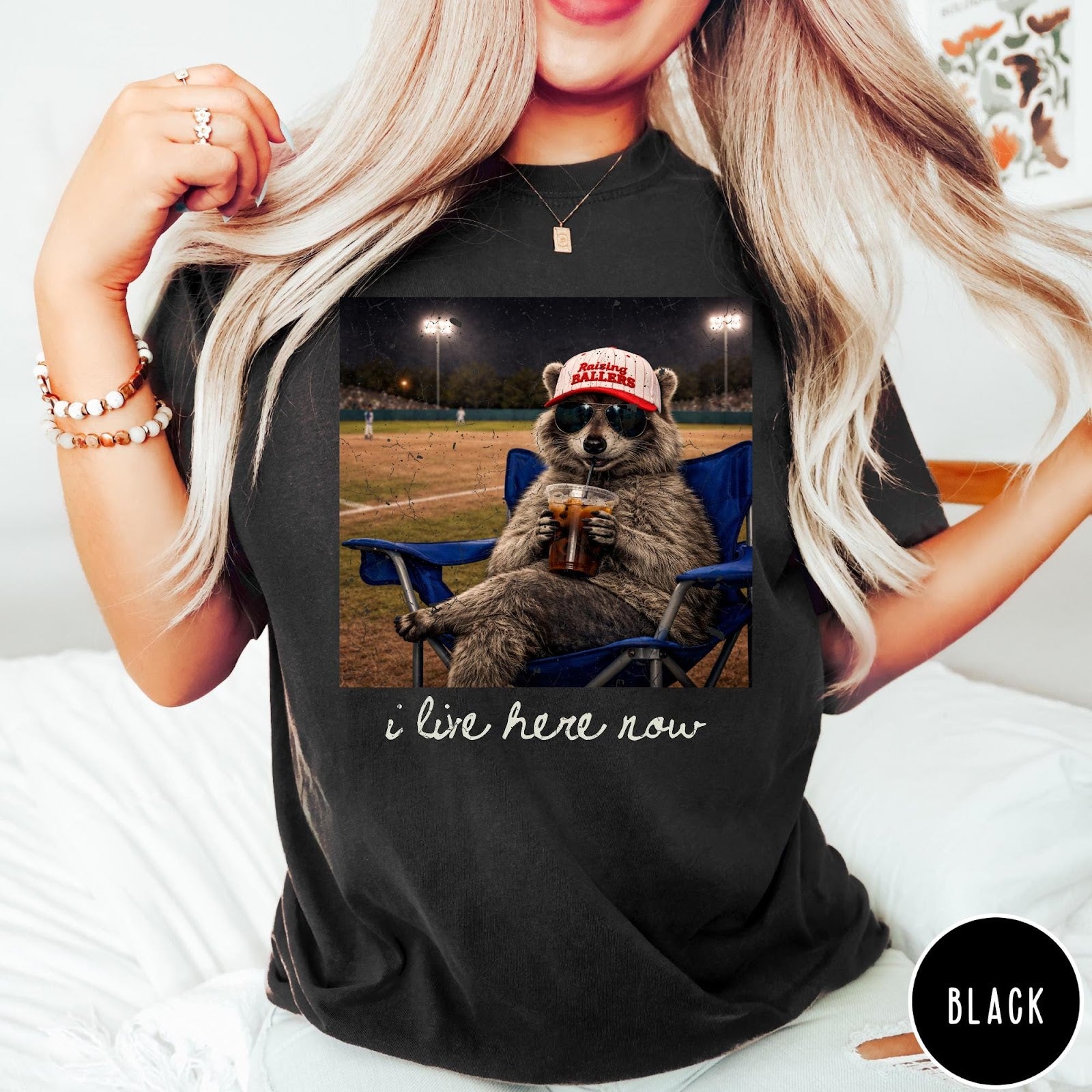 Comfort Colors tee in Black featuring graphic style raccoon wearing sunglasses and baseball cap at a stadium