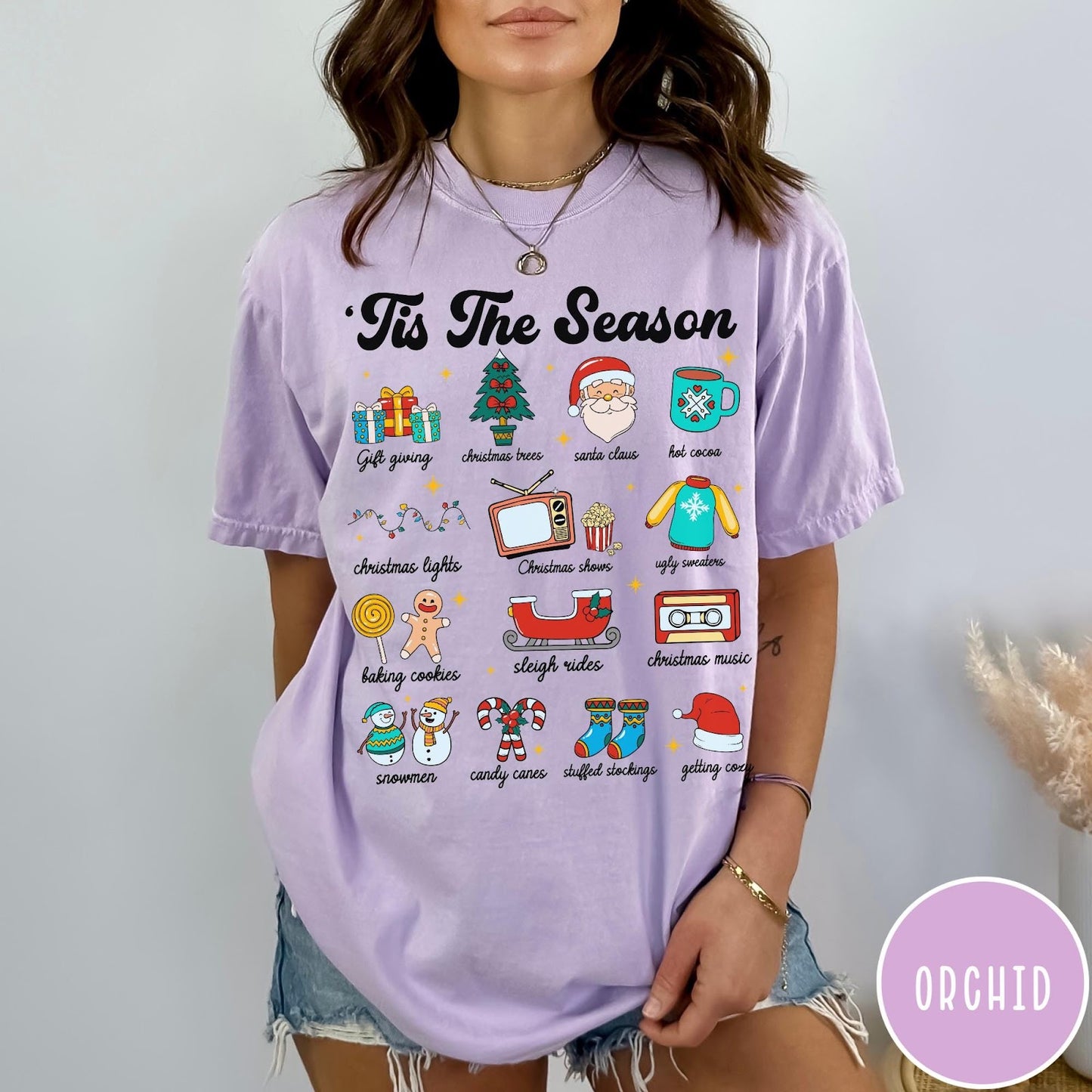 Comfort Colors tee in Orchid featuring holiday icons graphic with Christmas trees, Santa, and festive seasonal imagery