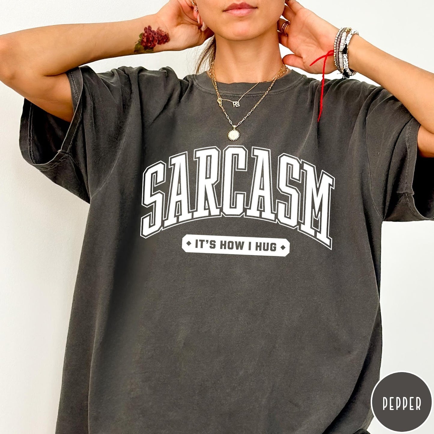 Comfort Colors tee in Pepper featuring collegiate style text reading Sarcasm It's How I Hug