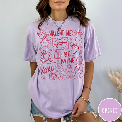 Comfort Colors tee in Orchid featuring sketch style Valentine's Day collage graphic with cupid, bear, and hearts