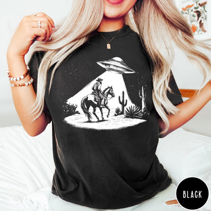 Comfort Colors tee in Black featuring western graphic style cowboy on horseback being abducted by a UFO
