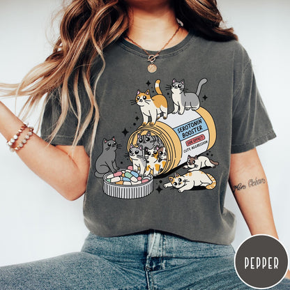 Comfort Colors tee in Pepper featuring graphic illustration of cats spilling out of a serotonin booster bottle