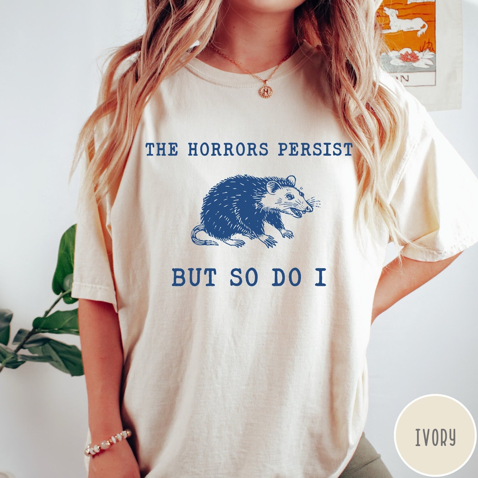 Comfort Colors tee in Ivory featuring illustrative style opossum graphic with text The Horrors Persist But So Do I