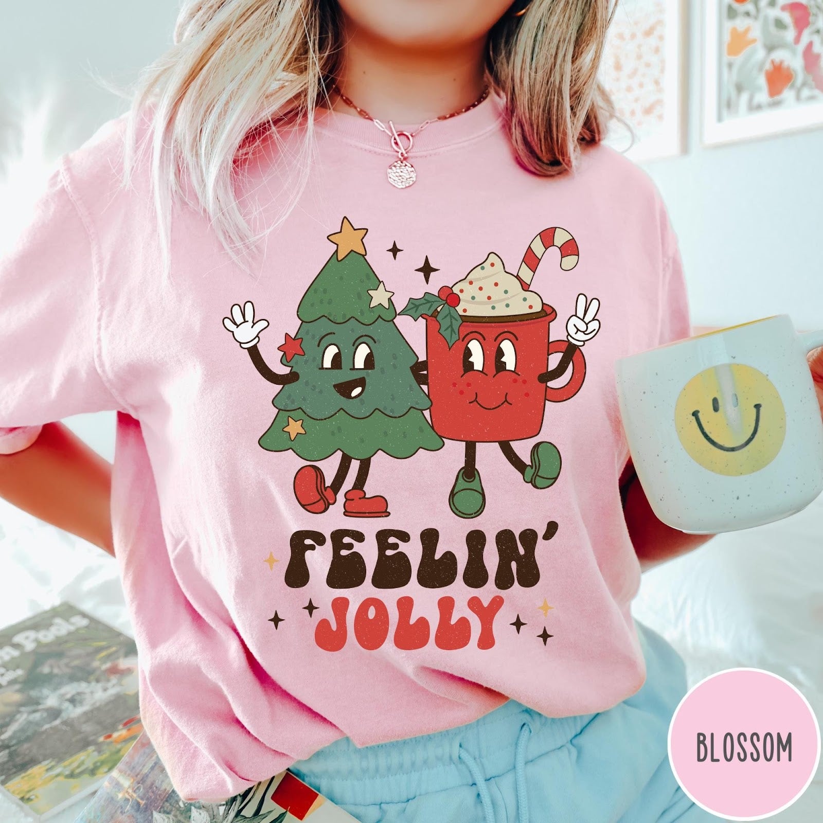 Comfort Colors tee in Blossom featuring retro style graphic of a cartoon Christmas tree and cocoa mug