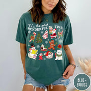 Comfort Colors tee in Blue Spruce featuring Christmas collage graphic with Santa, snowman, animals, and holiday icons
