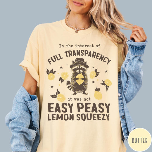 Comfort Colors tee in Butter featuring graphic illustration of a raccoon wearing a hat holding a lemon