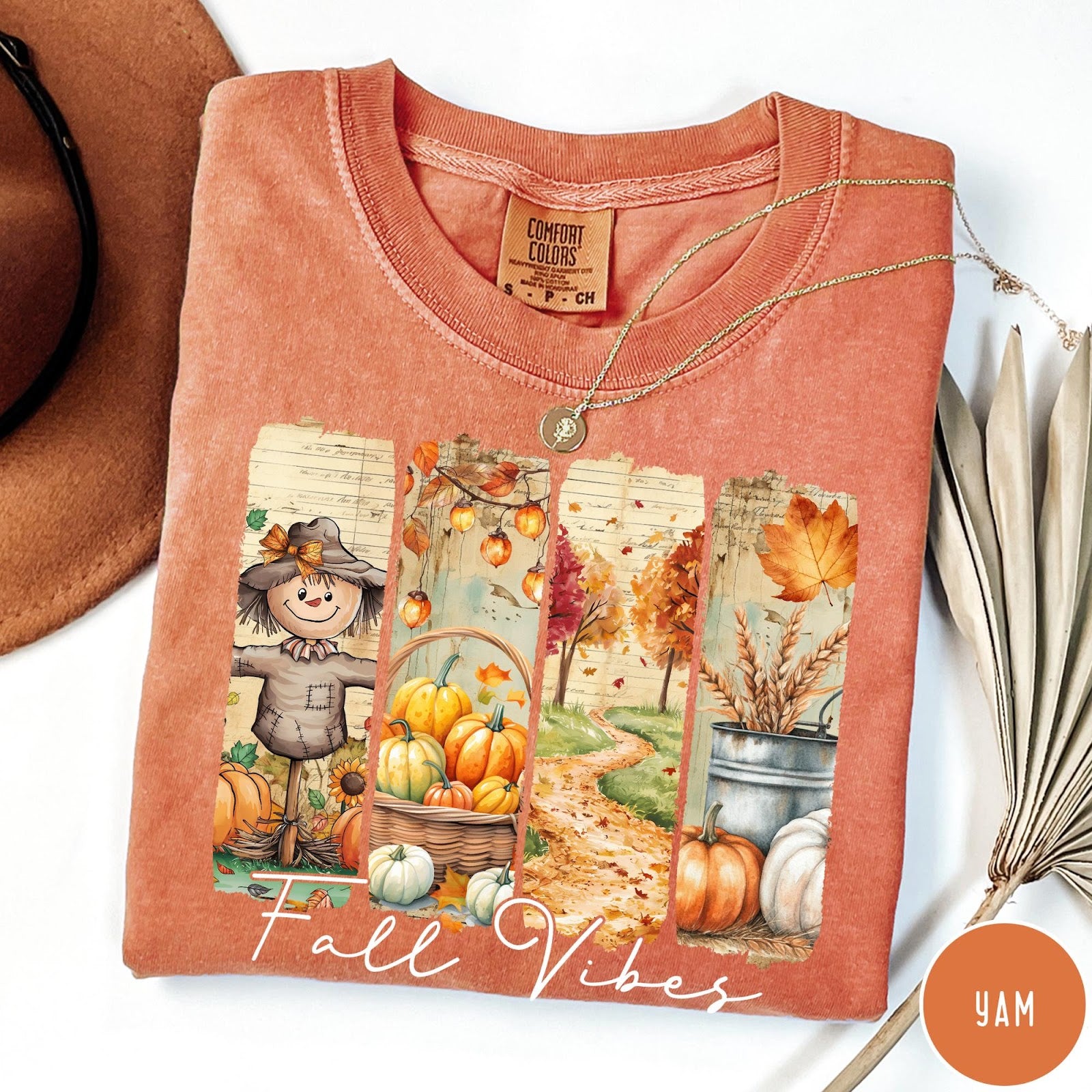 Comfort Colors tee in Yam featuring autumn harvest graphic with a scarecrow, pumpkins, and fall foliage scenes