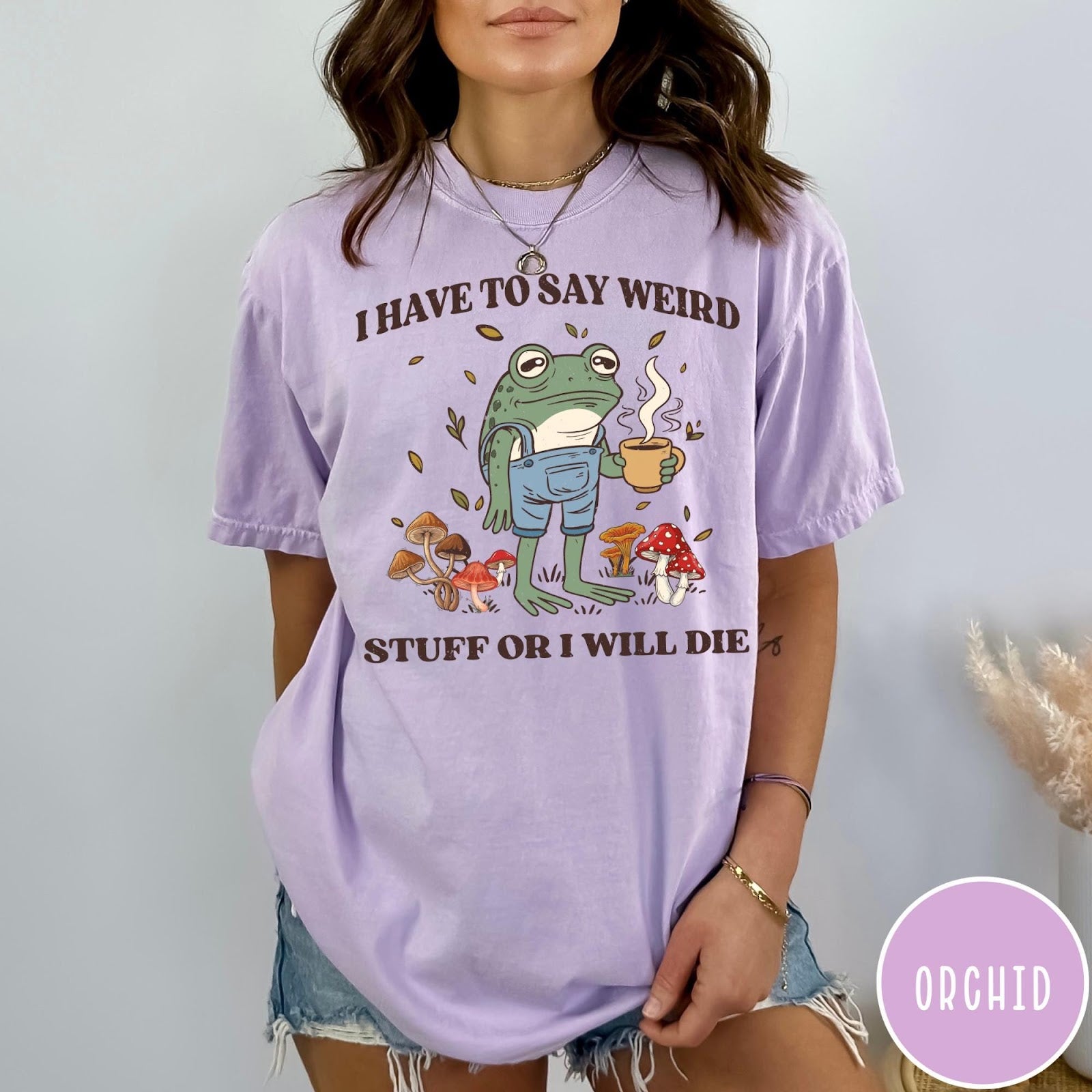 Comfort Colors tee in Orchid featuring cartoon style frog wearing overalls holding a coffee mug with mushrooms