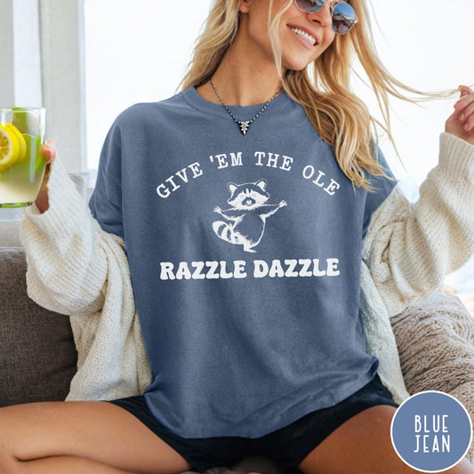 Comfort Colors tee in Blue Jean featuring whimsical raccoon graphic with Give Em The Ole Razzle Dazzle text