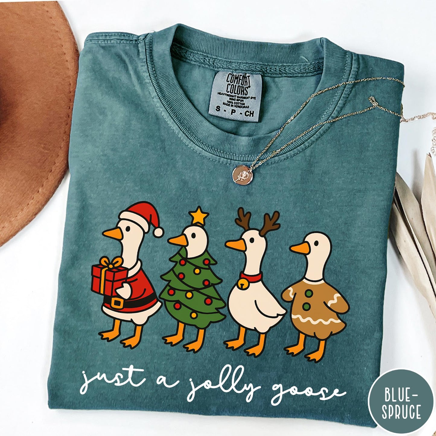 Comfort Colors tee in Blue Spruce featuring festive geese dressed as Santa, Christmas tree, reindeer, and gingerbread