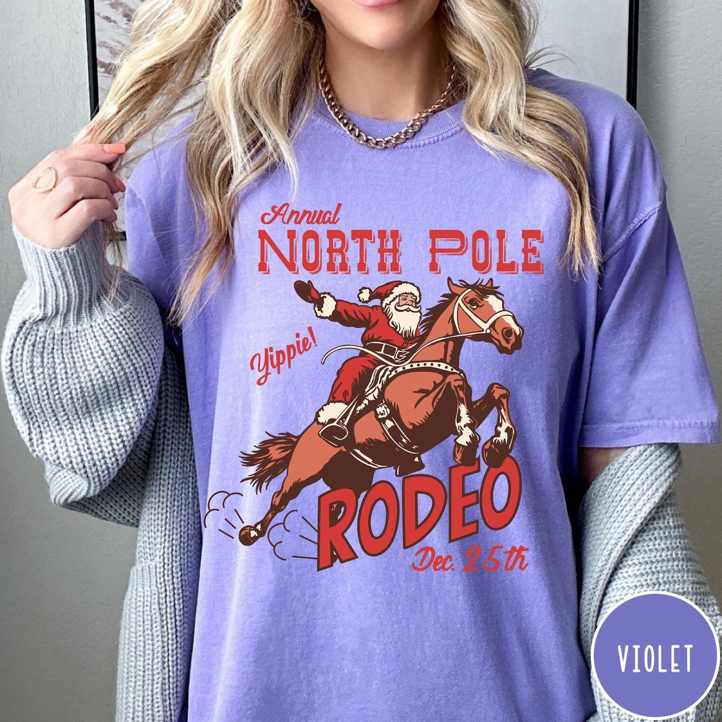 Comfort Colors tee in Violet featuring vintage style graphic of Santa Claus riding a bucking rodeo horse