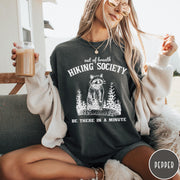Comfort Colors tee in Pepper featuring outdoor style graphic of a raccoon standing in the forest
