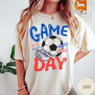 Comfort Colors tee in Ivory featuring soccer graphic with a ball, cleats, and Game Day text