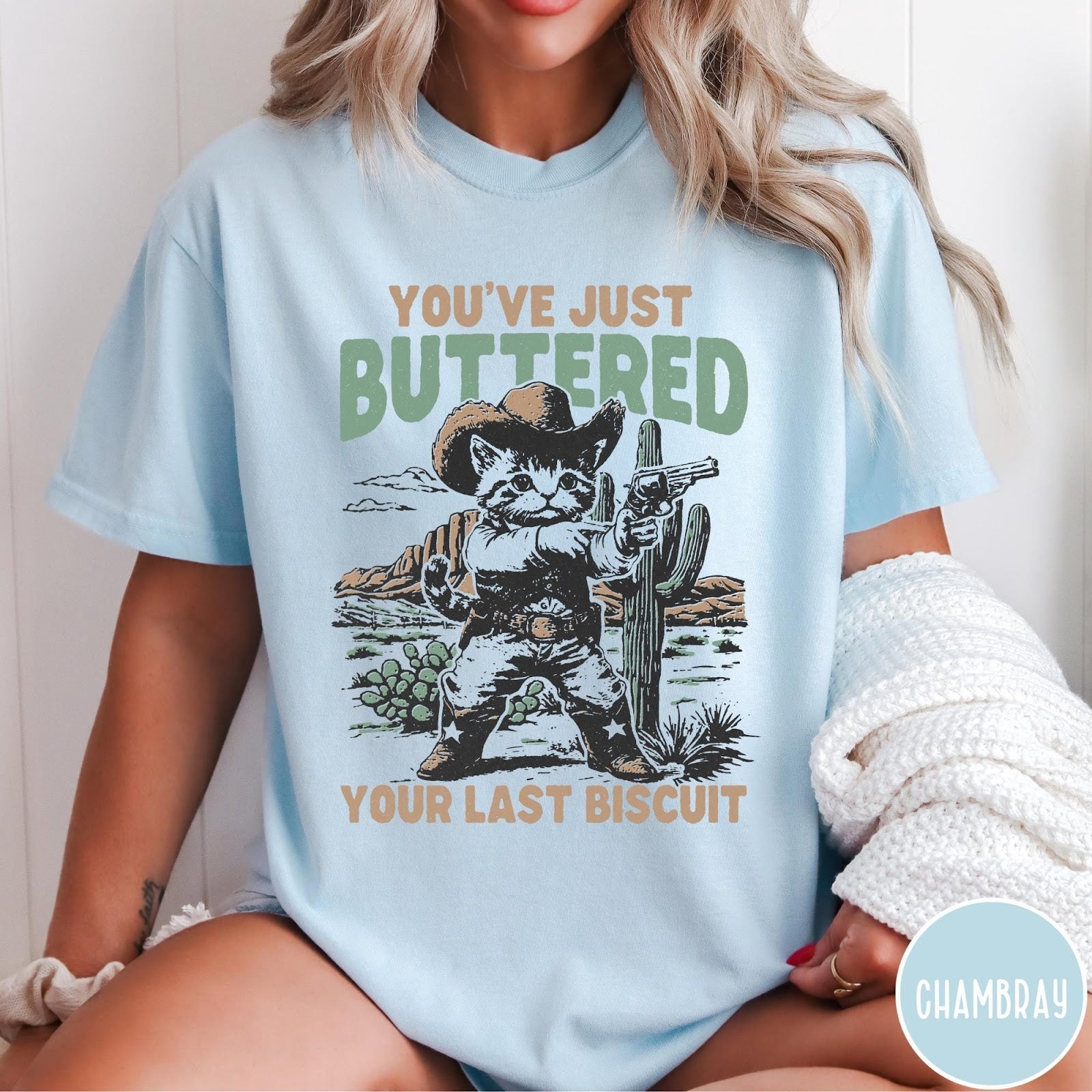 Comfort Colors tee in Chambray featuring western graphic design of a cat wearing a cowboy hat and gun.