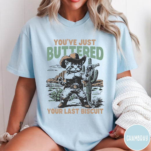 Comfort Colors tee in Chambray featuring western graphic design of a cat wearing a cowboy hat and gun.