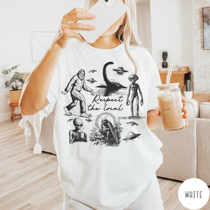 Comfort Colors tee in White featuring vintage style cryptid graphic with Bigfoot, UFOs, and alien creatures.