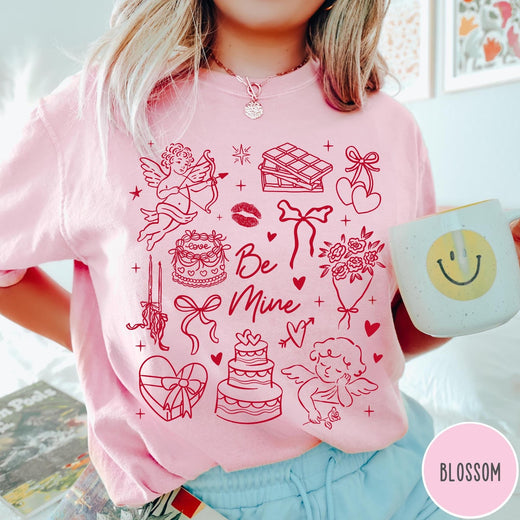 Comfort Colors tee in Blossom featuring Valentine's Day collage design with cupid, cake, flowers, and chocolate graphics