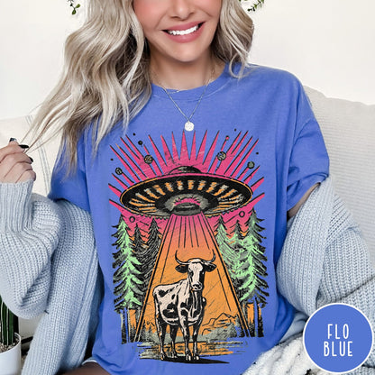 Comfort Colors tee in Flo Blue featuring graphic style cow being abducted by a UFO in the forest