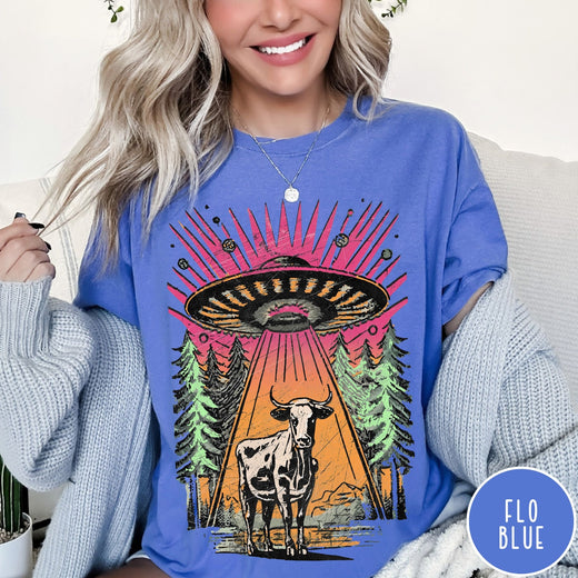Comfort Colors tee in Flo Blue featuring graphic style cow being abducted by a UFO in the forest