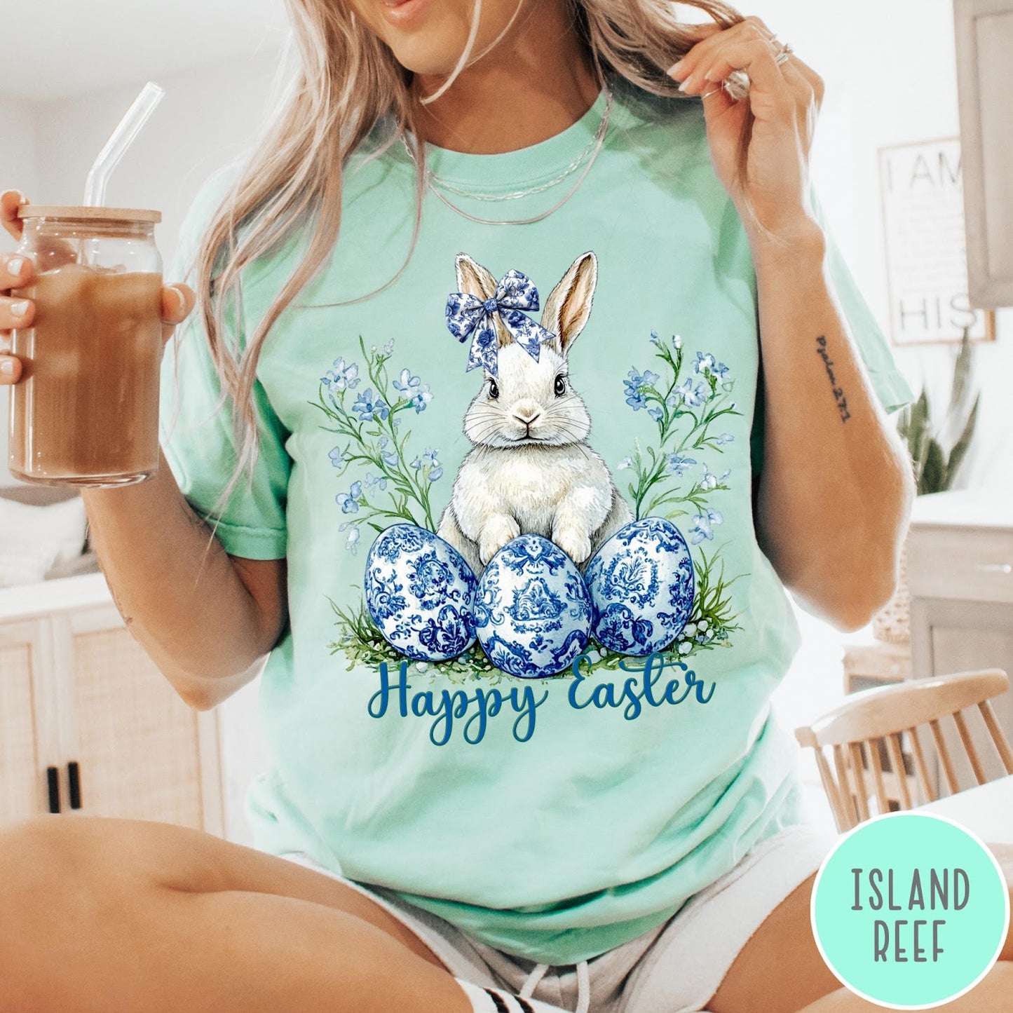 Comfort Colors tee in Island Reef featuring Easter bunny graphic with blue floral bow and patterned Easter eggs
