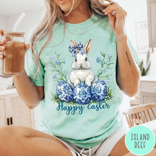 Comfort Colors tee in Island Reef featuring Easter bunny graphic with blue floral bow and patterned Easter eggs
