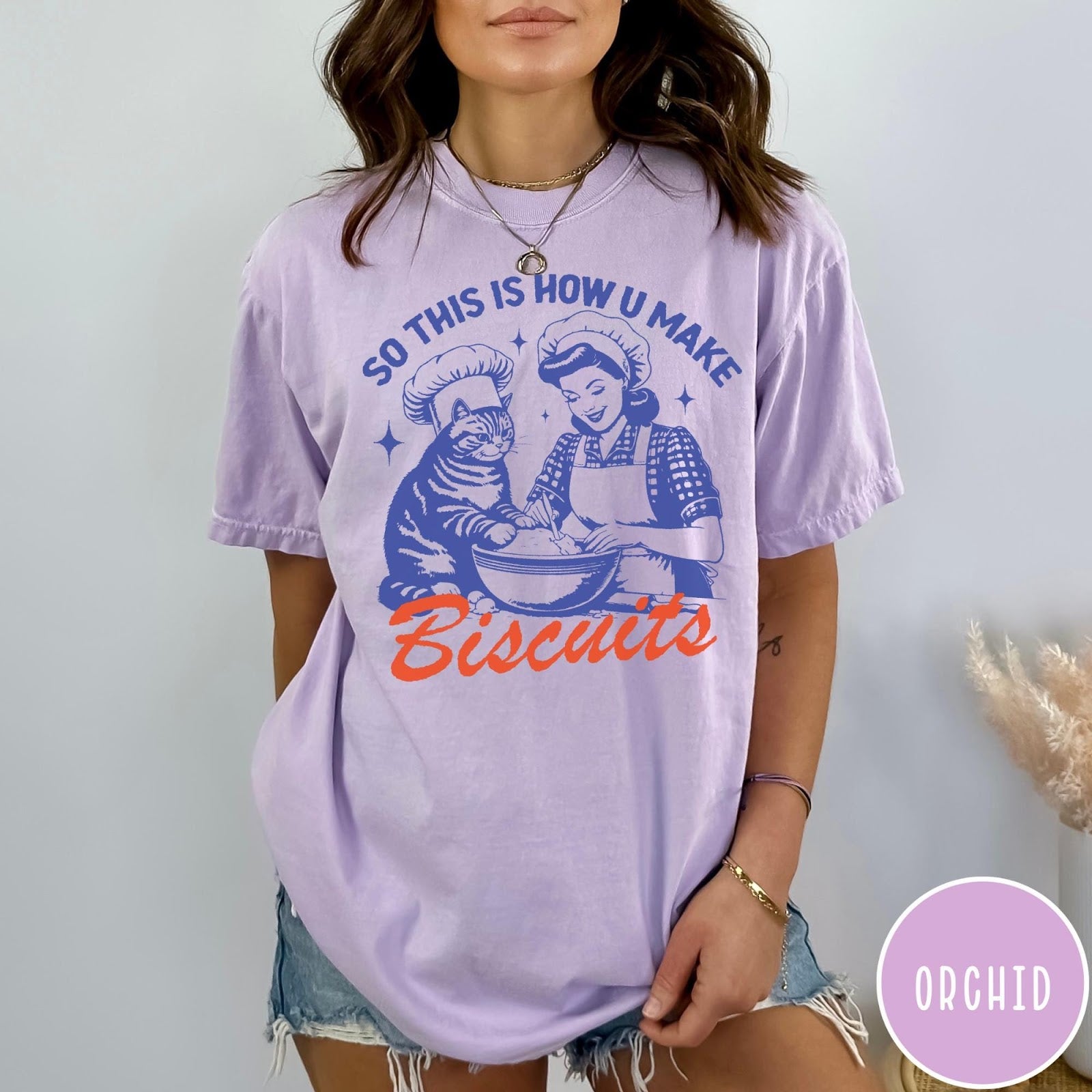 Comfort Colors tee in Orchid featuring vintage style graphic of a woman and cat baking biscuits together