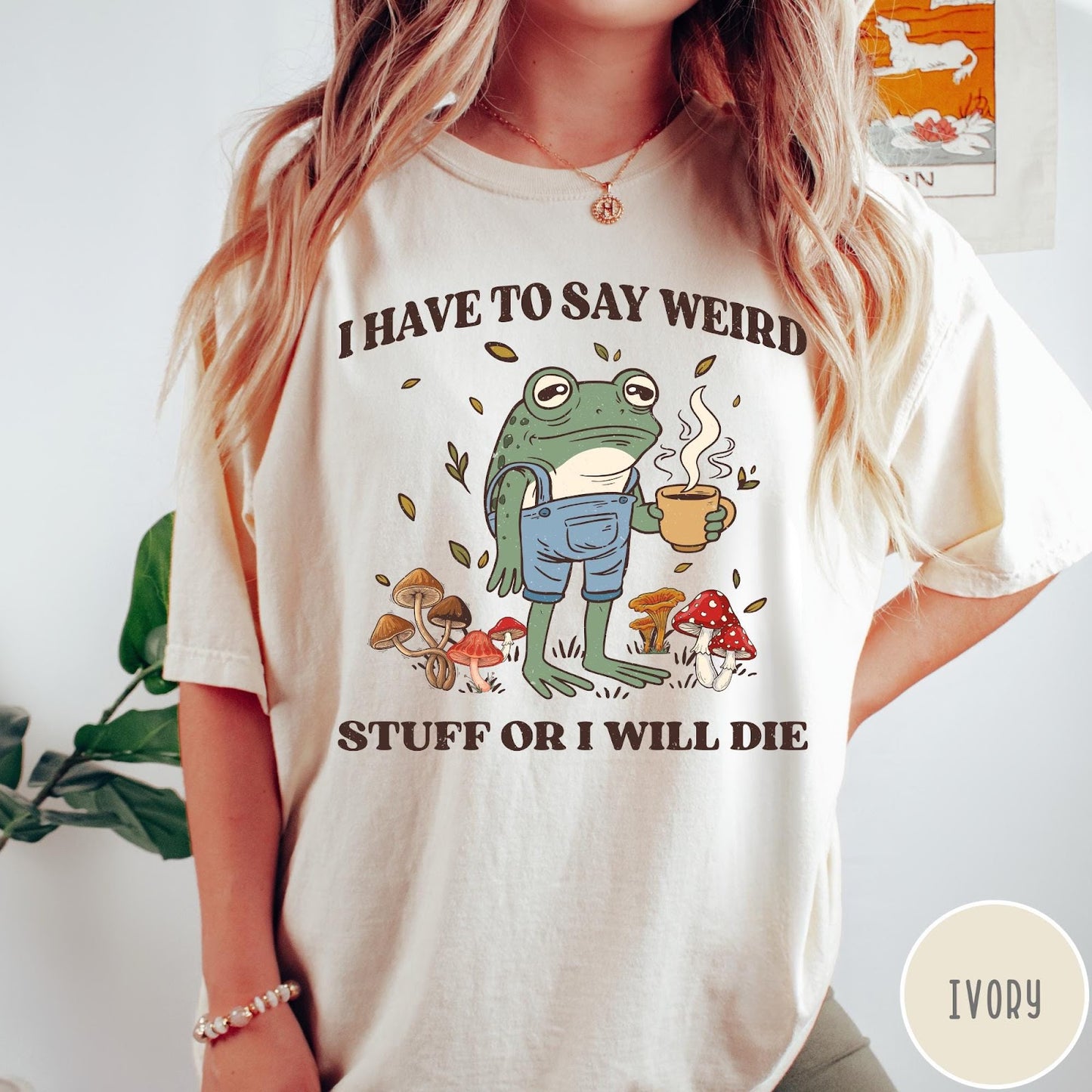 Comfort Colors tee in Ivory featuring illustrative frog graphic with coffee cup and various forest mushrooms