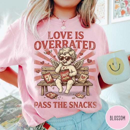 Comfort Colors tee in Blossom featuring vintage style graphic of a cherub eating snacks on a bench