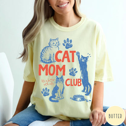 Comfort Colors tee in Butter featuring graphic illustration of cats, paw prints, and Cat Mom Club text