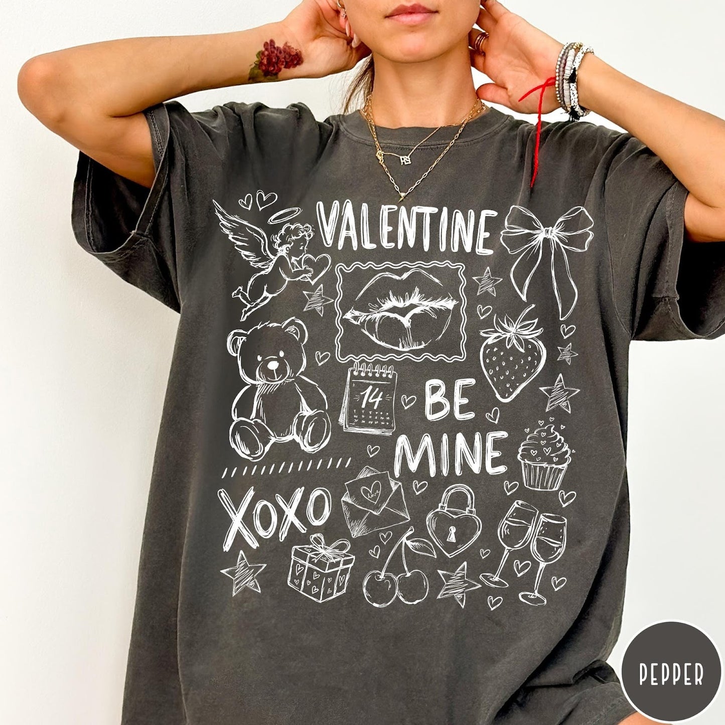 Comfort Colors tee in Pepper featuring sketch style Valentine's Day collage graphic with cupid, bear, and hearts