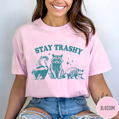 Comfort Colors tee in Blossom featuring graphic style raccoon, skunk, and opossum wearing sunglasses with Stay Trashy text