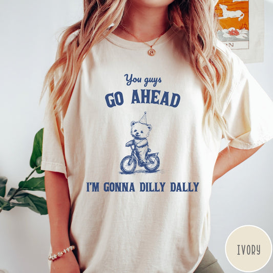 Comfort Colors tee in Ivory featuring illustration style graphic of a bear wearing a party hat riding bicycle