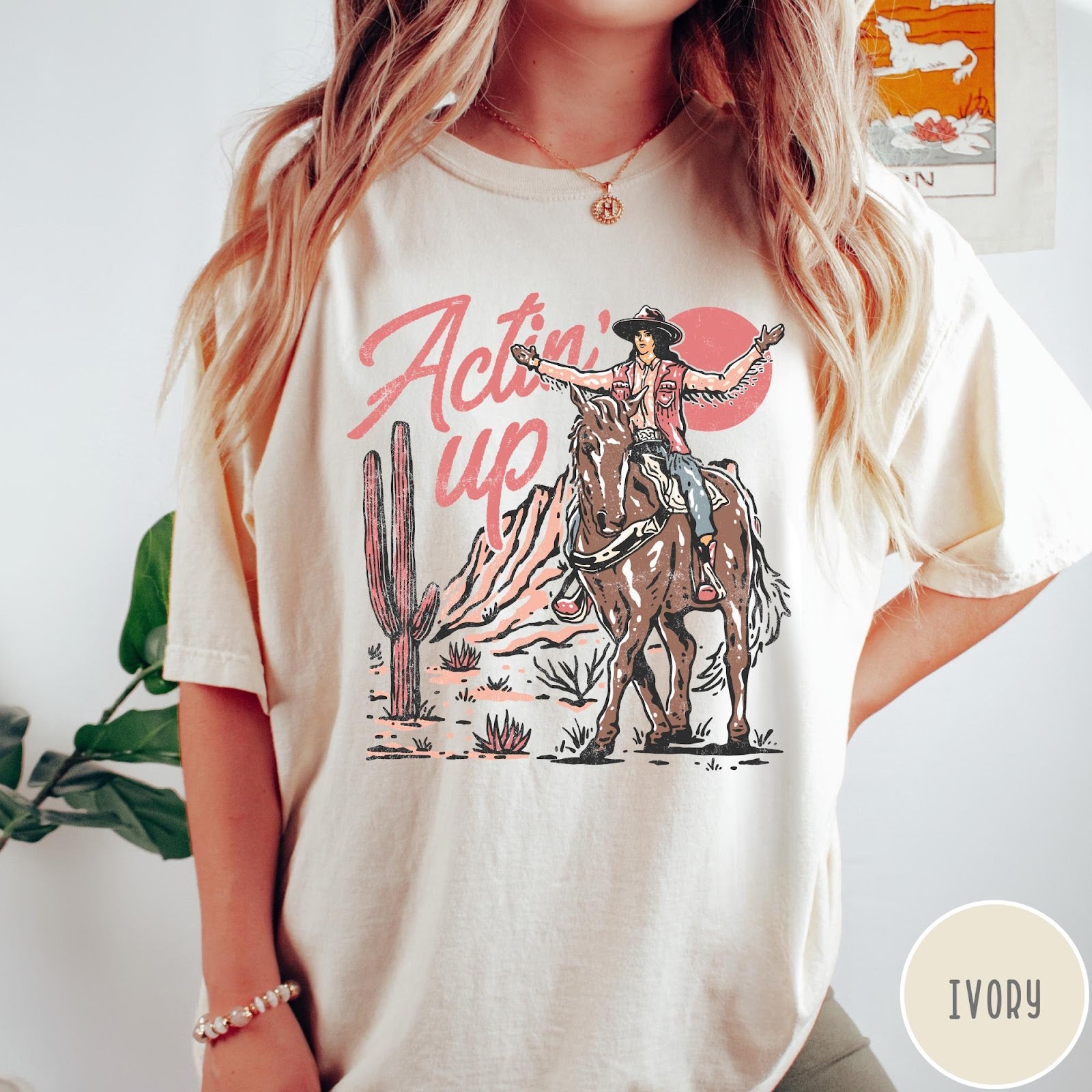 Comfort Colors tee in Ivory featuring western style graphic of a cowgirl riding a horse in the desert