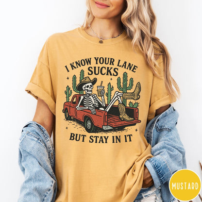 Comfort Colors tee in Mustard featuring western skeleton graphic with cowboy hat and boots in pickup truck