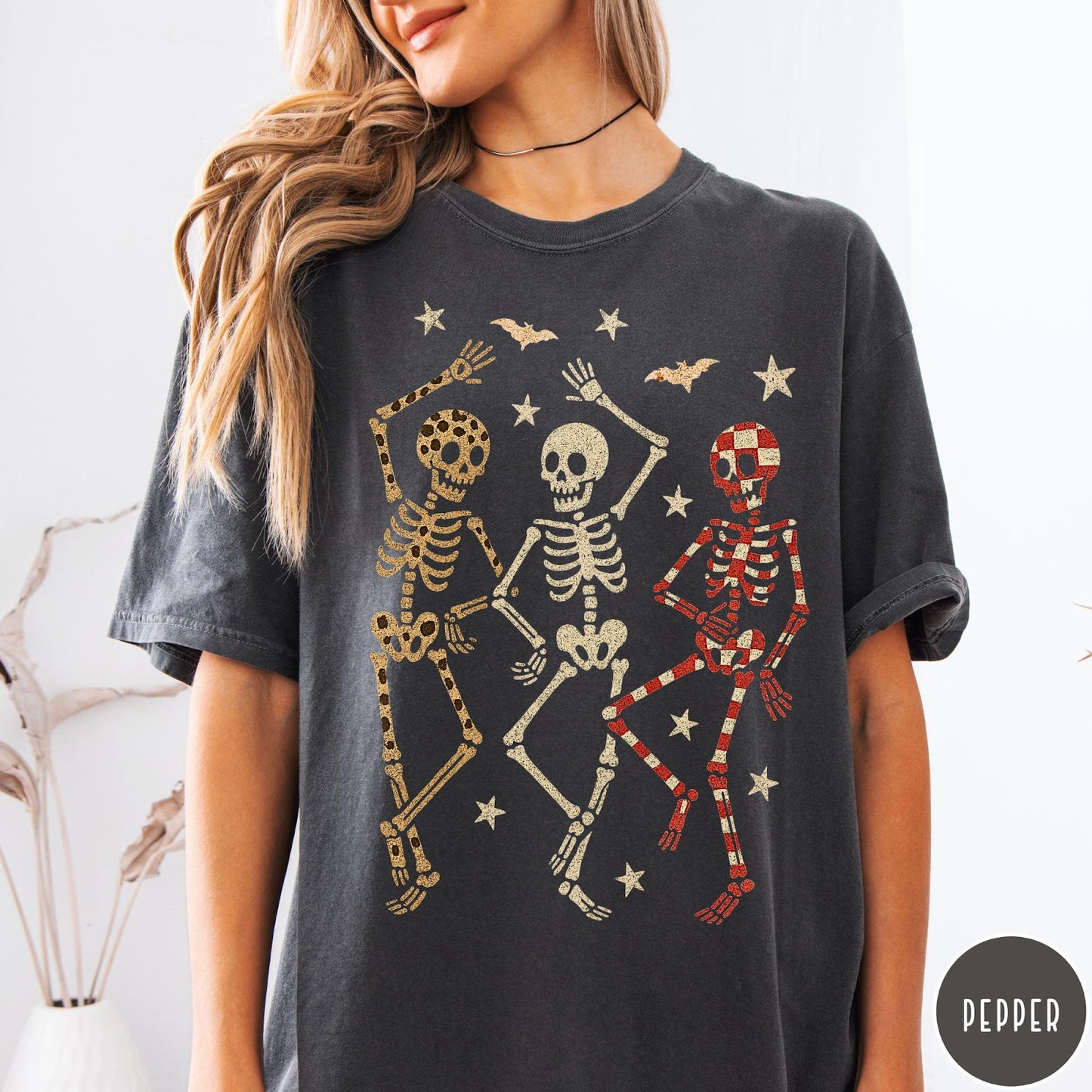 Comfort Colors tee in Pepper featuring dancing skeletons design with three skeletons, stars, and bats graphic