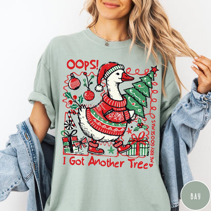 Comfort Colors tee in Bay featuring festive goose graphic wearing a Santa hat and Christmas sweater holding tree