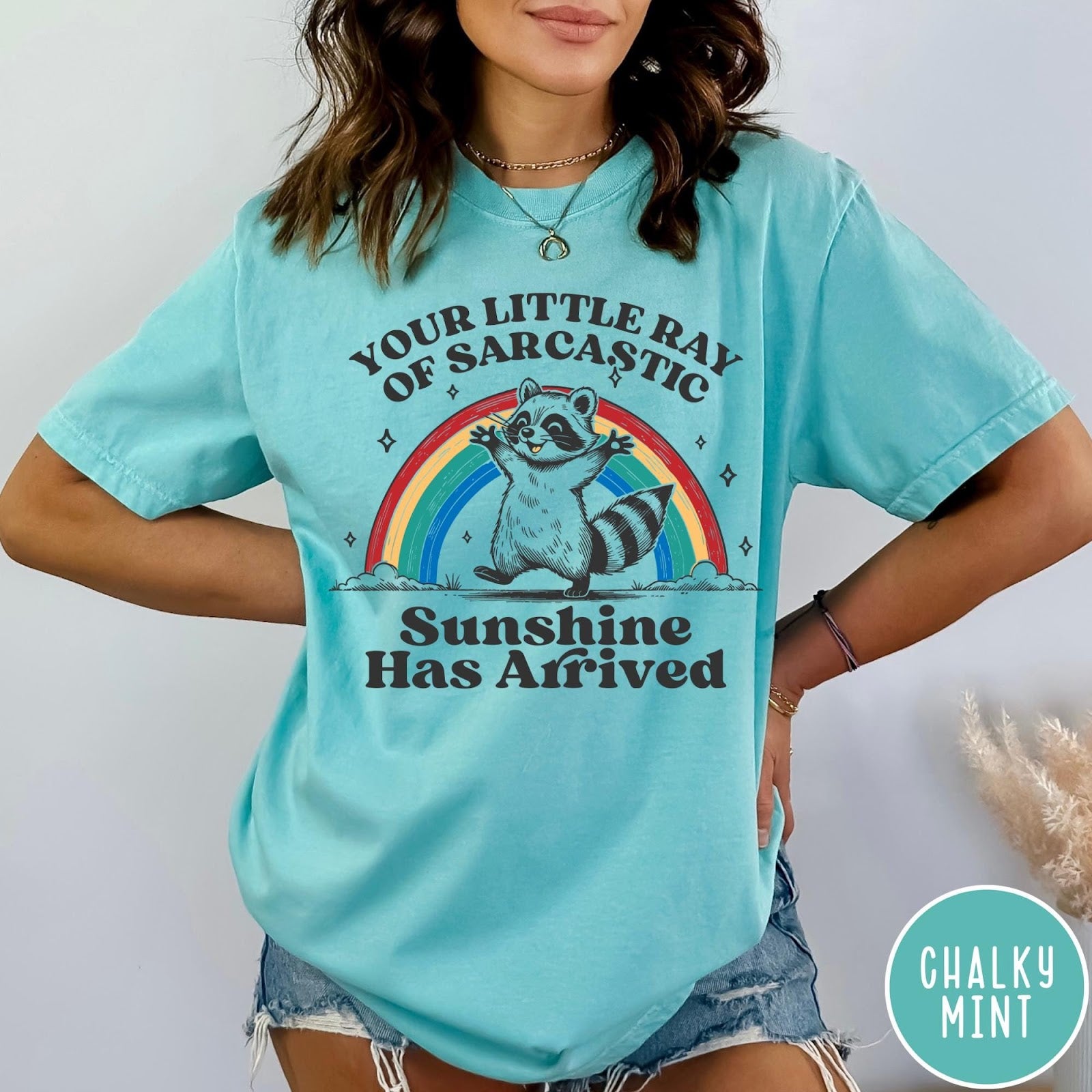 Comfort Colors tee in Chalky Mint featuring vintage style graphic of a happy raccoon standing before a colorful rainbow