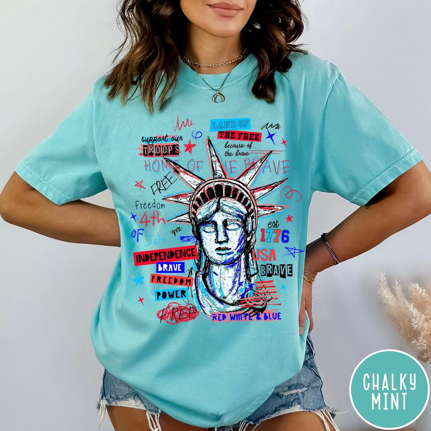 Comfort Colors tee in Chalky Mint featuring grunge style Statue of Liberty graphic with patriotic red and blue text