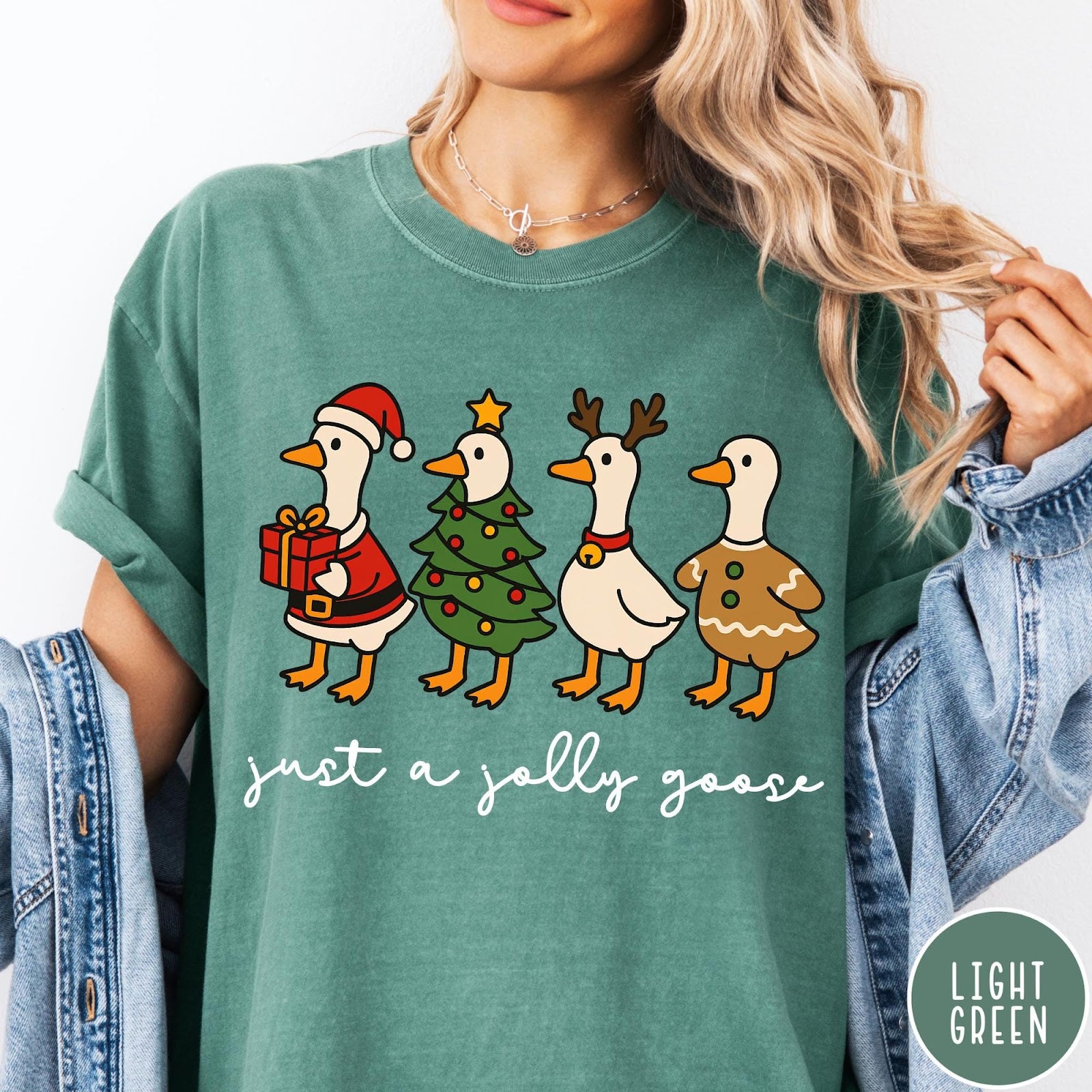 Comfort Colors tee in Light Green featuring festive geese graphic with Santa, Christmas tree, reindeer, and gingerbread goose designs