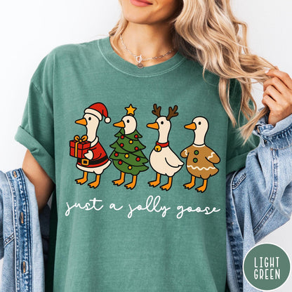 Comfort Colors tee in Light Green featuring festive geese graphic with Santa, Christmas tree, reindeer, and gingerbread goose designs