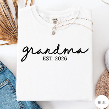 Comfort Colors tee in White featuring script design Grandma Est. 2026 announcement graphic in black