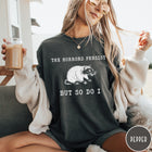 Comfort Colors tee in Pepper featuring illustrative style opossum graphic with text The Horrors Persist But So Do I